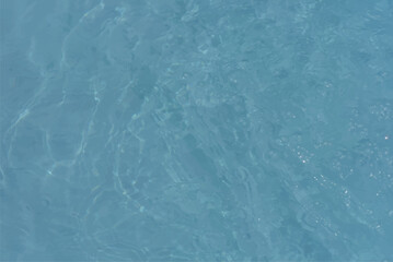 Blue water with ripples on the surface. Defocus blurred transparent blue colored clear calm water surface texture with splashes and bubbles. Water waves with shining pattern texture background.