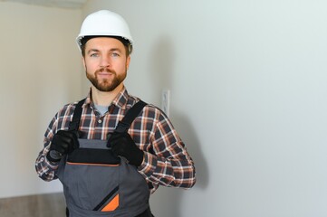 Portrait of positive, handsome young male builder while working at construction site.