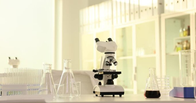 Microscope and glass flasks in empty medical laboratory