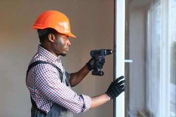 African Handyman Repairing Broken Window On Balcony