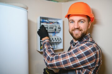 handsome young man electrician working on switchboard of house building construction site