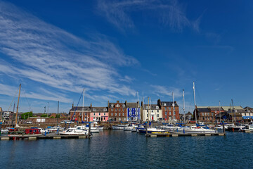 Looking at the traditional Fishermans Houses across the inner harbour and Marina of Arbroath Harbour on a bright day in June.