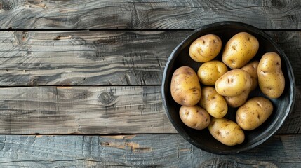 Organic farm new potatoes arranged on a black clay dish with a backdrop of gray wooden surface - Powered by Adobe
