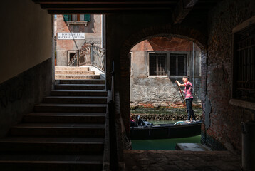 Gondola passing by stone opening to a canal in Venice, Italy.