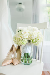 Bridal bouquet and cream shoes in white wooden chair