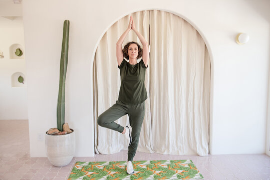 White women doing yoga in home with cactus behind