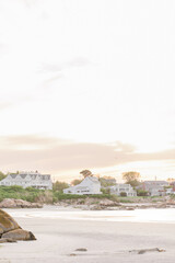 Coastal homes and rocky shoreline at Wingaersheek Beach during sunset