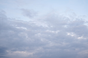 Soft blue sky combines with light of sunset to create a peaceful sky. Beautiful landscape with clouds and orange sun.