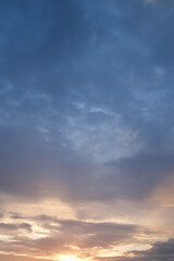 Obraz premium Soft blue sky combines with light of sunset to create a peaceful sky. Beautiful landscape with clouds and orange sun. Vertical image.