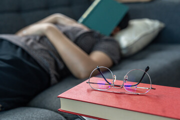 A young woman fell asleep reading a book on the couch at home