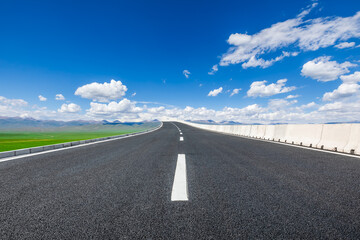 Asphalt highway road and green meadow with mountain nature landscape under blue sky