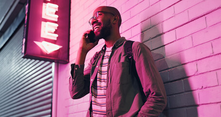 Happy man, conversation and neon light with phone at night for communication outside bar, pub or...