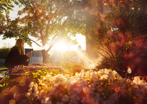 Teenager watering garden bright sunny day
