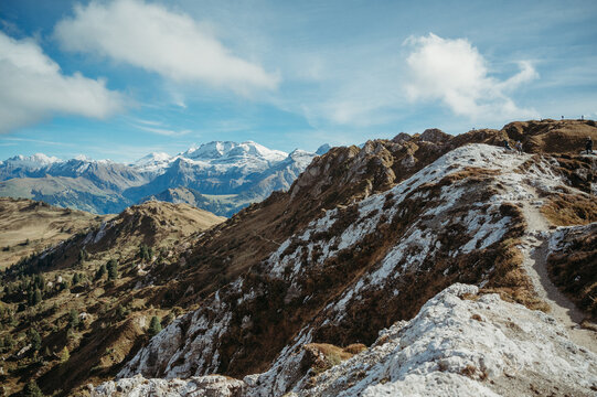 Swiss mountain peaks in Lenk under a bright blue sky with clouds.