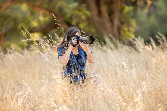 Women taking photo in tall dead grass kneeling