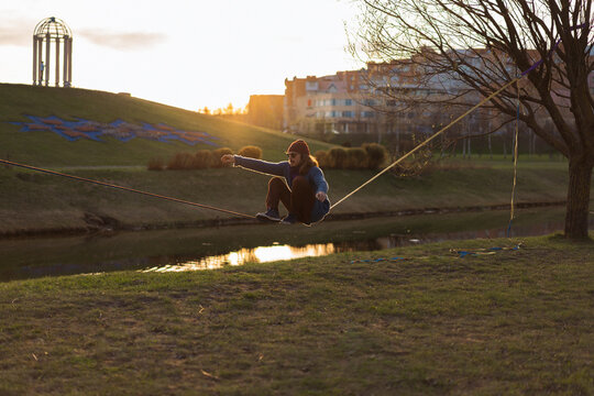 Young man sitting on a slackline.