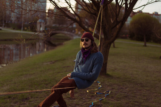 Young man sitting on a slackline.