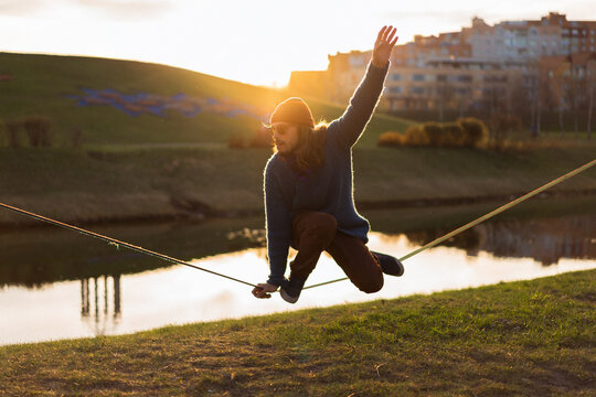 Young man sitting on a slackline.