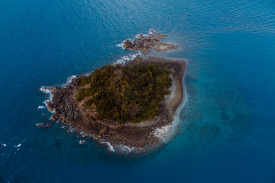 Aerial view of an isolated tiny island surrounded by crystal waters