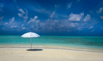 Summer tropical with white umbrella on the beach with  blue sky background