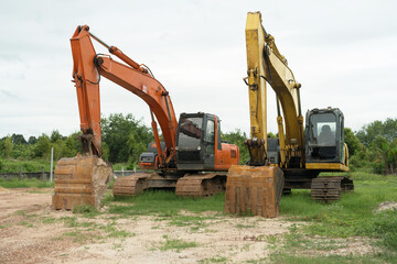 Three excavators parked on grass and a cloudy day