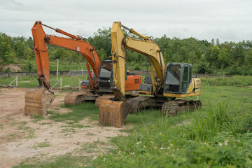 Three excavators parked on grass and a cloudy day