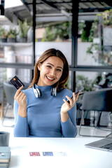 Businesswoman hand hold mock-up credit card for online shopping on smartphone or laptop computers from home office, payment e-commerce, internet finance bank, spend money electronic wallet
