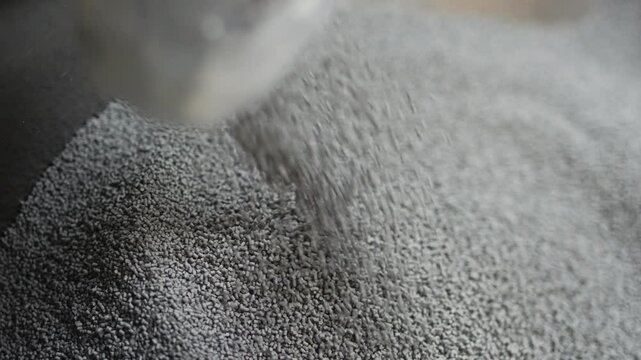 Filling the tank with plastic granules. The process of producing parts from polyethylene compound. Grey granules are poured into a container. Slow motion (4K)