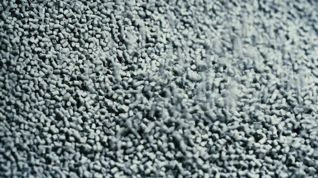 Filling the tank with plastic granules. The process of producing parts from polyethylene compound. Grey granules are poured into a container. Close up (4K)