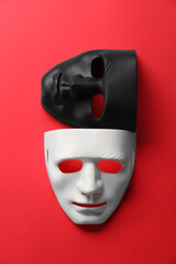 Theater arts. White and black masks on red background, top view