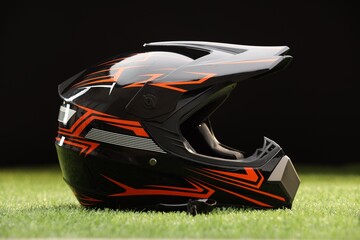 Modern motorcycle helmet with visor on green grass against black background