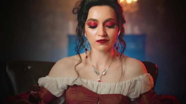 Two women vampires. beauty woman black hair Fantasy lady evil face queen sitting on throne vampire girl biting victim in neck drinking blood sharp fangs red lips. dark night room candles light art 4k