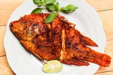 fried fish dish in a plate on a wooden table