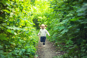 Portrait of smiling girl runs on the trail in the deciduous forest. Waving hands. Forest on bright light background.