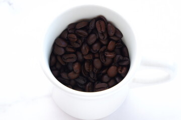 コーヒーカップと、深煎りしたコーヒー豆
