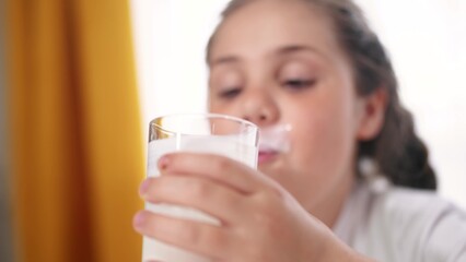 child dirty drinks milk. healthy a eating children concept. child girl drinks milk in the kitchen stained lips lifestyle funny rejoices smiling. daughter whale drinks milk