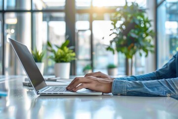 A person is typing on a laptop in front of a potted plant. Concept of productivity and focus, as the person is engaged in their work. The presence of the plant adds a touch of nature