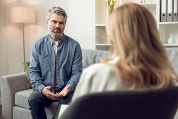 Woman psychologist discusses solutions and support with her troubled male patient in office