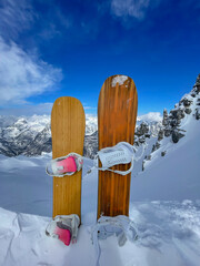 Two snowboards stuck in pile of snow on top of freeride line with fresh snowpack