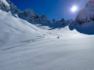 Snowy mountain slope with fresh tracks and skier enjoying on fresh powder