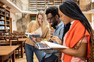 Young people studying in the library together and looking involved