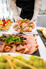 Waiter in black uniform and white gloves serving gourmet ham canapés at an upscale event, focus on food with blurred background