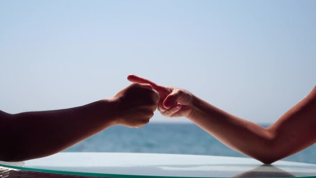 Rock paper scissors being played by two young woman. Close up view female hands playing stone, scissors and paper on sea background, funny carefree game. Friendship, dealing with conflict, having fun.