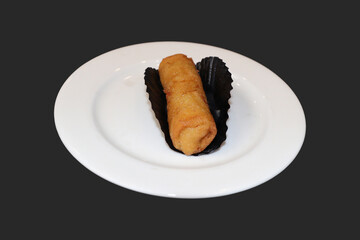 Fried spring rolls on a white plate, lined with black baking paper