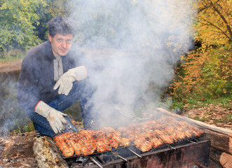 mature men make barbecue on the grill in nature against the backdrop of the river