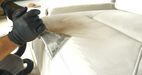 CLOSE UP: Deep cleaning of white upholstered sofa surface with vacuum cleaner