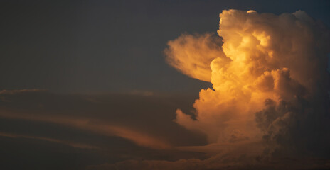 Dramatic sunset clouds with dark blue and vibrant orange hues, creating an atmospheric and serene...