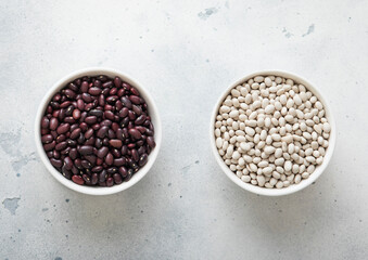 Ceramic bowls with white and red raw dry beans on kitchen table.Macro.