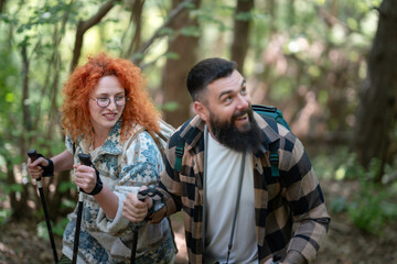 Fototapeta premium A beautiful and cheerful couple is hiking in the forest enjoying nature and each other's company