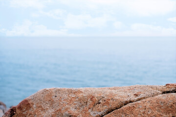 Rock Sea stones with texture surface with blurry blue ocean, cloud sky background,Aerial view Edge Cliff Rock natural stone located part of the mountain with blurred sea beach in sunny day summer